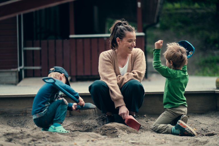 Bilde av to barn og en barnehageansatt som leker i sandkassen